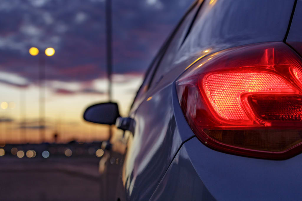 Close-up of car brake light glowing at dusk in a car park